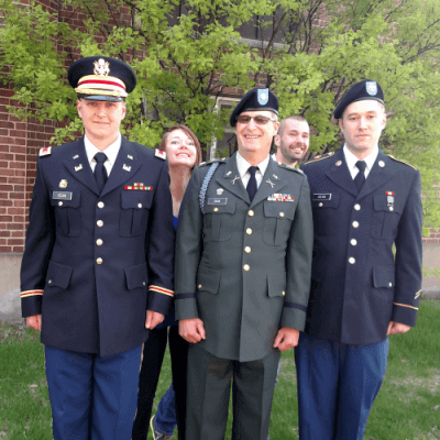 photo of the Dean family - father Tom Dean in dress greens army uniform, flanked by 2 sons in dress blues army uniforms with daughter and son peeking behind.