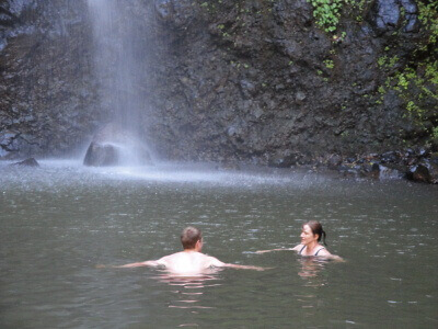 Becky Dean and her son swimming in a pool with a waterfall in the background