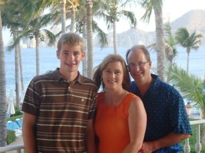 Tom & Becky Dean with their son in the Mexican Riviera - palm trees and ocean beyond