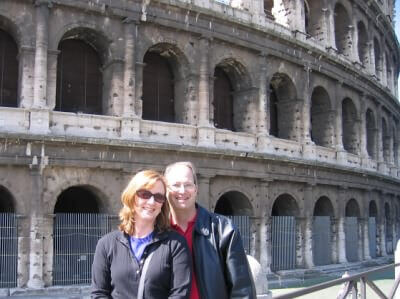 Tom & Becky Dean standing in front of the Coliseum in Rome