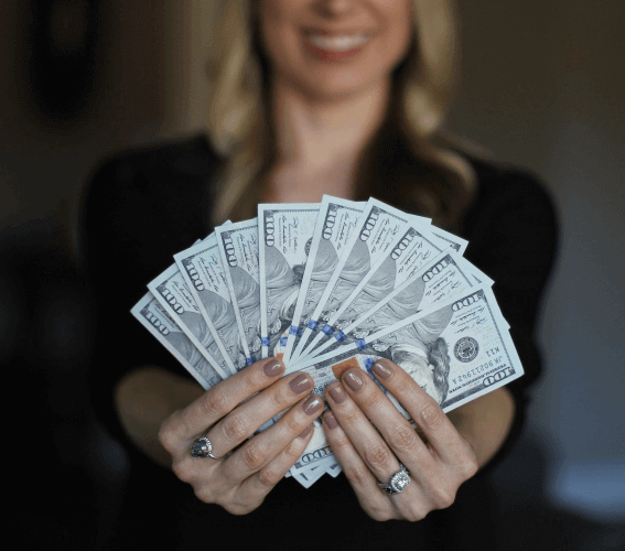 woman holding several 100 dollar bills