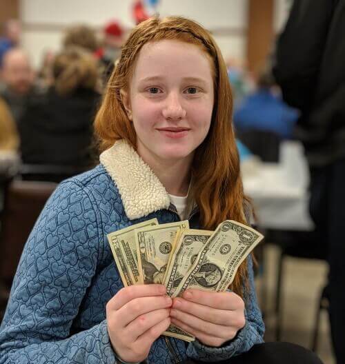 photo of a red-haired girl in a blue cardigan holding cash